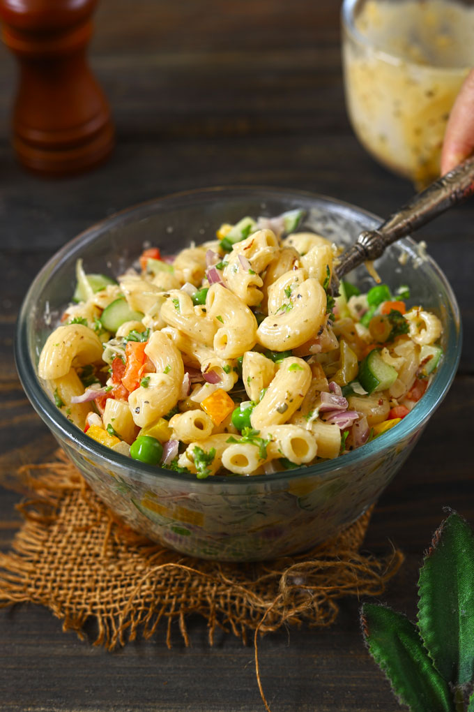 side shot of macaroni salad in a bowl with a serving spoon