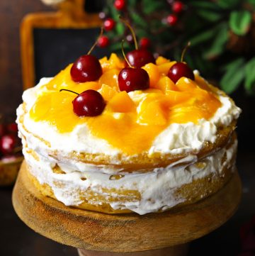 side close up shot of layered peach cake on a wooden cake stand