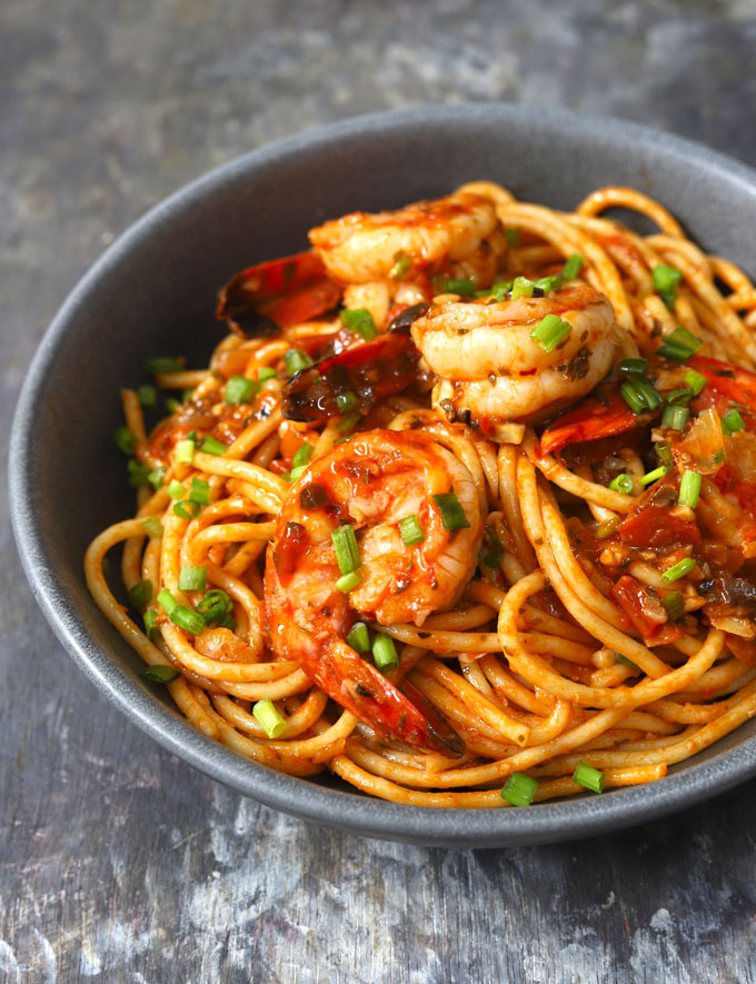 side close up shot of red sauce spaghetti with shrimp in a black ceramic serving bowl