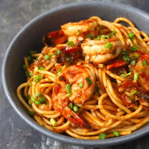 side close up shot of red sauce spaghetti with shrimp in a black ceramic serving bowl