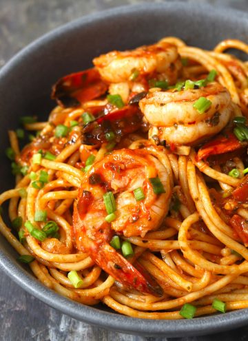side close up shot of red sauce spaghetti with shrimp in a black ceramic serving bowl