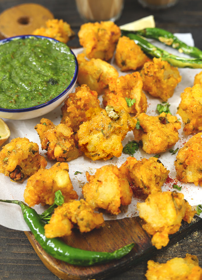 side shot of aloo pakora stacked on a platter with chutney