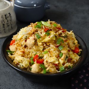 side shot of chicken fried rice in a black ceramic bowl