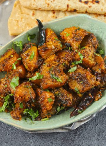 side shot of kaddu sabzi i a green ceramic bowl