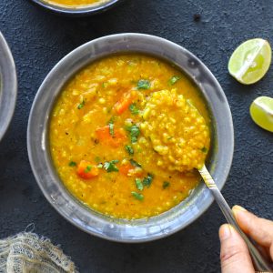 aerial shot of mulligatawny in a grey ceramic bowl with a spoon