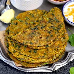 side shot of methi paratha stacked on a plate