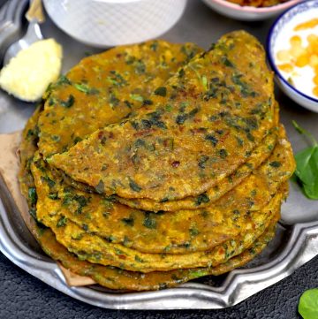 side shot of methi paratha stacked on a plate