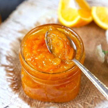 side shot of orange marmalade in a jar with the spoon