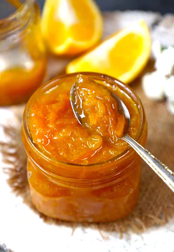 side shot of orange marmalade in a jar with the spoon