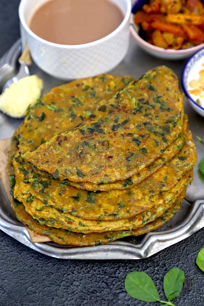 side shot of methi paratha stacked on a plate