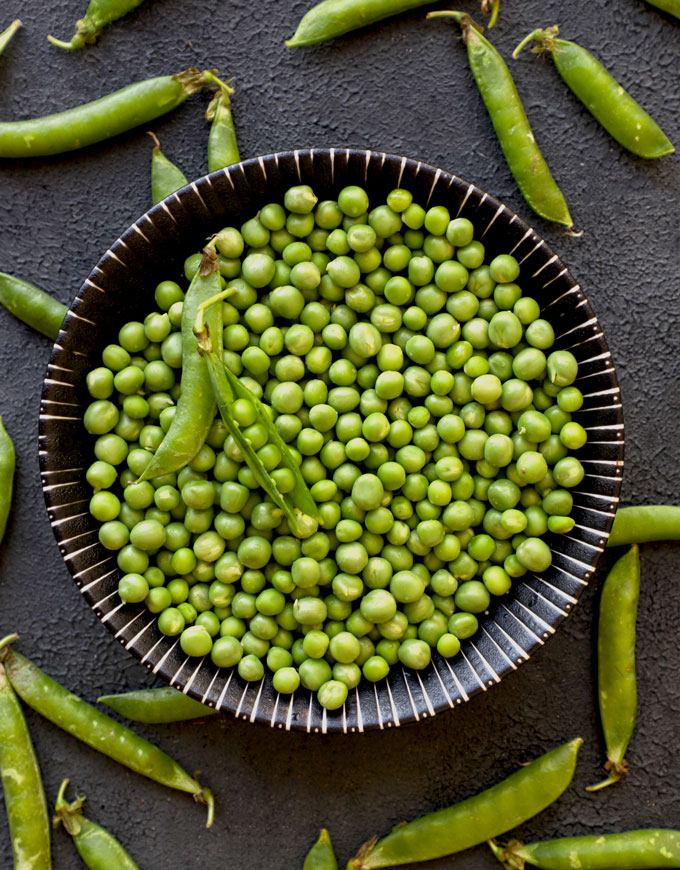 aerial shot of fresh green peas in a black ceramic bowl