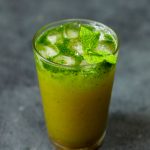 side shot of sugarcane juice in a glass with mint leaves