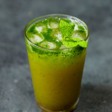 side shot of sugarcane juice in a glass with mint leaves