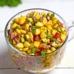 side shot of corn chaat in a glass mug