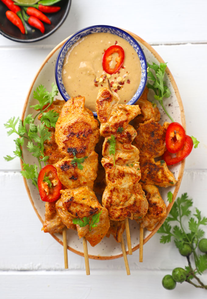 aerial shot of chicken satay on a platter with peanut dipping sauce. 