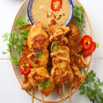 aerial shot of chicken satay with peanut dipping sauce on a platter