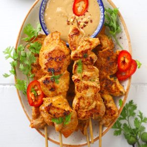 aerial shot of chicken satay with peanut dipping sauce on a platter