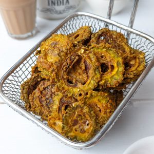 side shot of karela chips on a wire basket