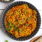 aerial shot of kamal kakdi ki sabji in a black ceramic bowl