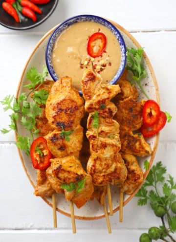 aerial shot of chicken satay on a platter with peanut dipping sauce.