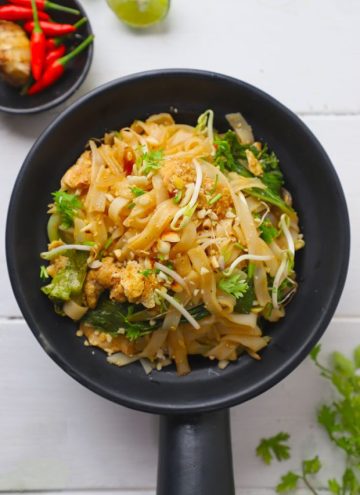aerial shot of chicken pad thai in a black serving bowl