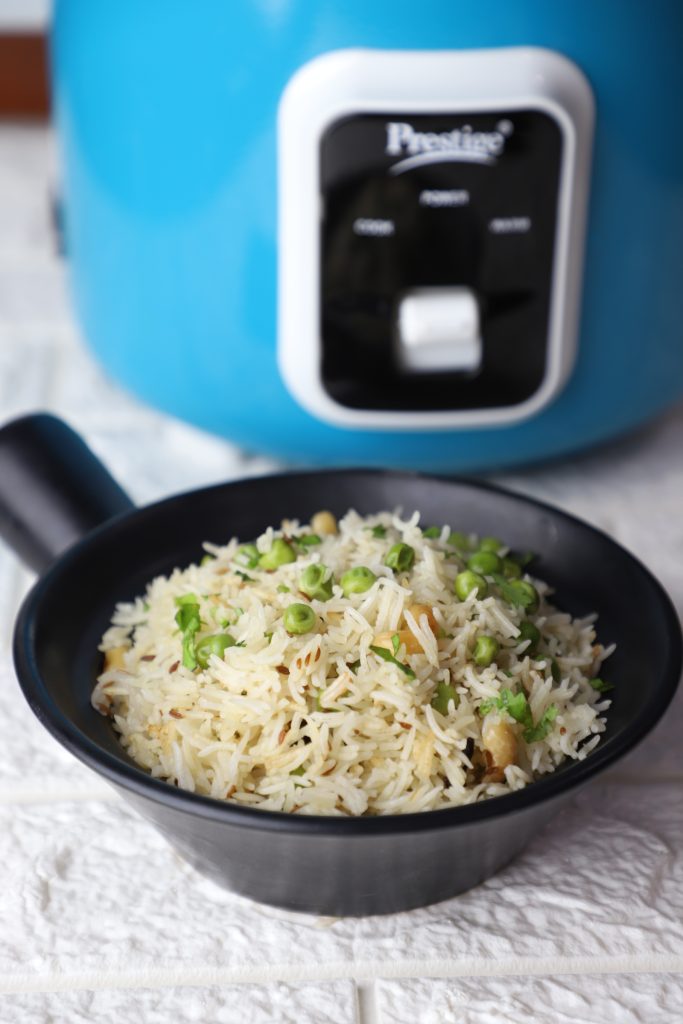 side shot of matar pulao in a black ceramic bowl