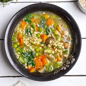 aerial shot of vegetable barley soup in a black ceramic bowl