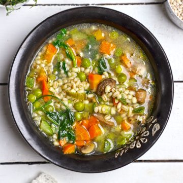 aerial shot of vegetable barley soup in a black ceramic bowl