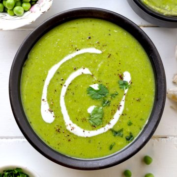 aerial shot of green pea soup in a black ceramic bowl