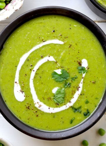 aerial shot of green pea soup in a black ceramic bowl