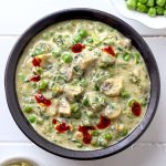 aerial shot of mushroom methi matar malai in a black ceramic bowl.