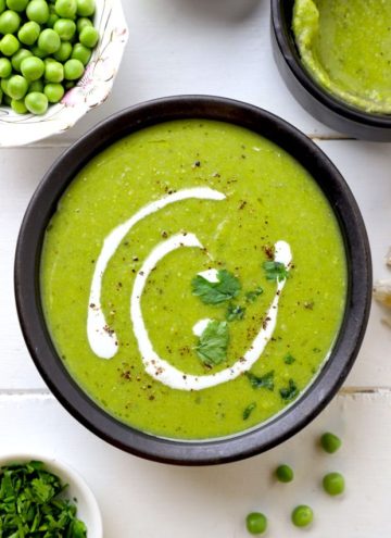 aerial shot of green pea soup served in a black ceramic bowl