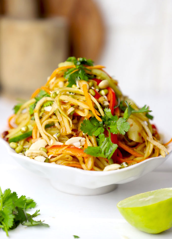 side shot of green papaya salad stacked on a white bowl