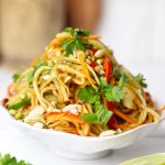 side shot of green papaya salad stacked on a platter