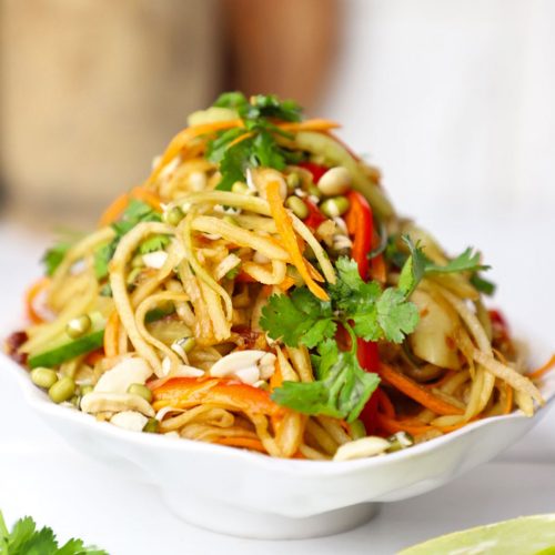 side shot of green papaya salad stacked on a platter