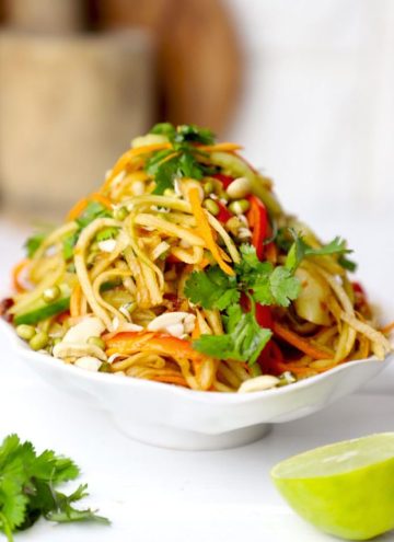 side shot of green papaya salad stacked on a white bowl