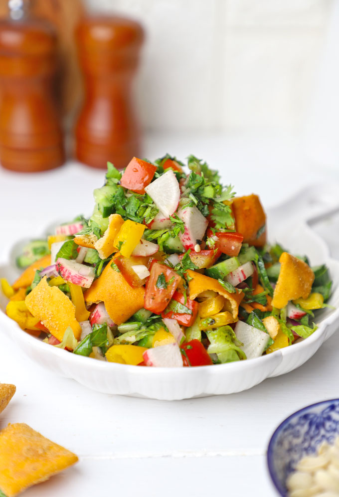 side shot of fattoush salad stacked on a white ceramic platter