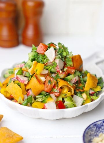 side shot of fattoush salad stacked on a white ceramic platter