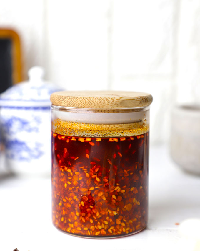 side shot of homemade chilli oil in a glass bottle with a wooden lid