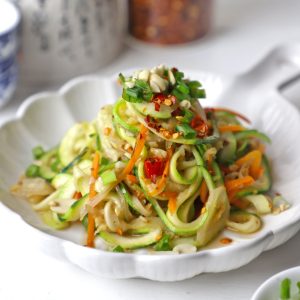 side close up shot of stir fry zoodles in a white ceramic platter