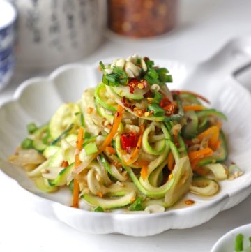 side close up shot of stir fry zoodles in a white ceramic platter