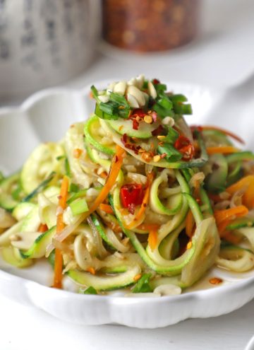 side close up shot of stir fry zoodles in a white ceramic platter