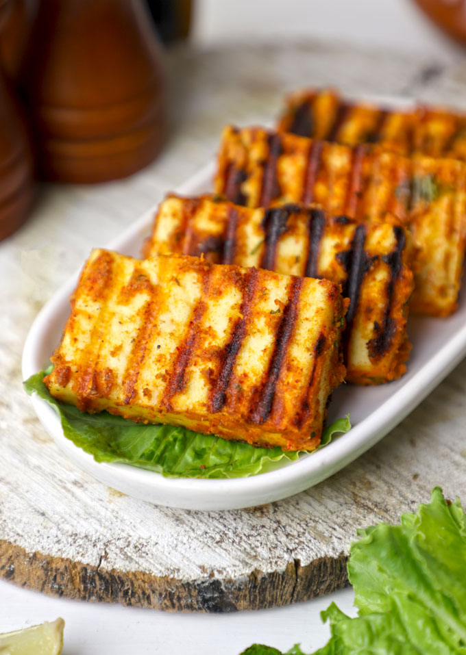 side shot of grilled paneer served in a white platter