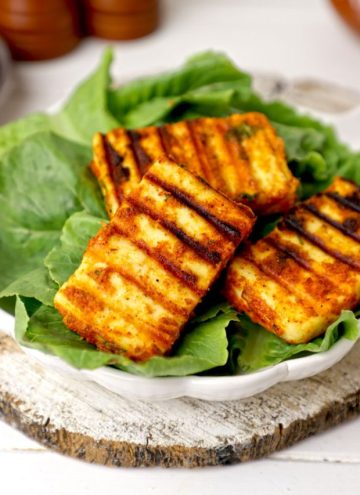 side shot of grilled paneer served on lettuce leaves