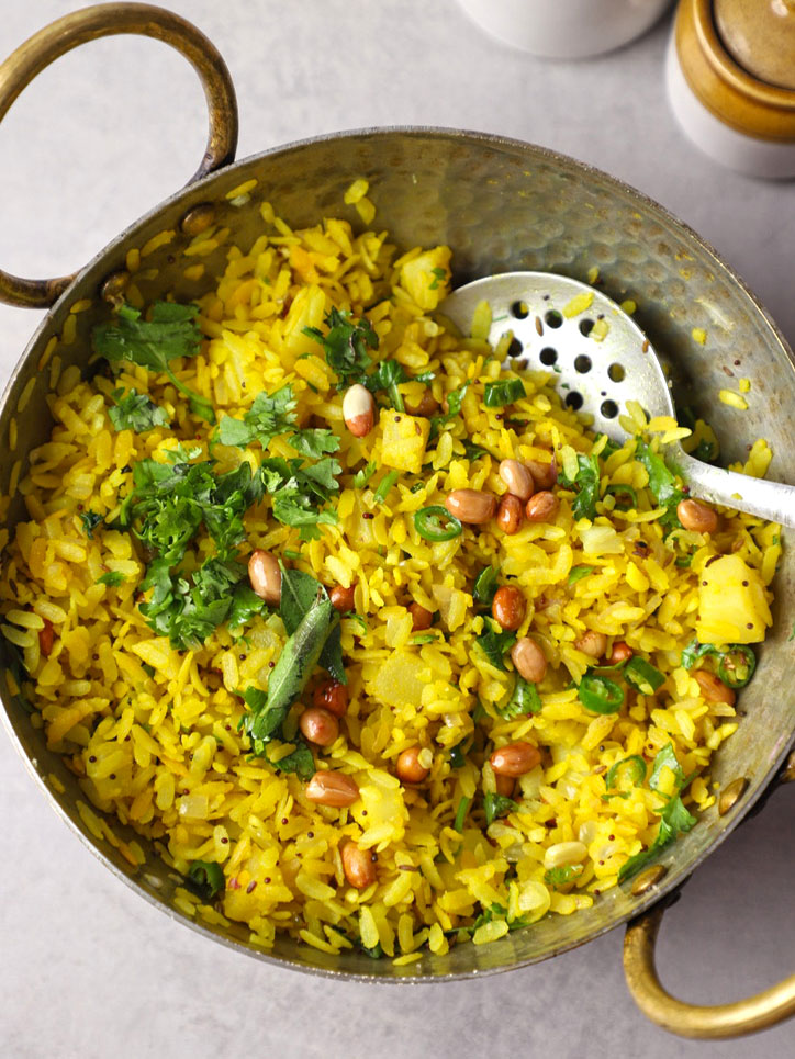 aerial shot of kanda poha in a kadhai with a serving spoon