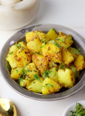 side close up shot of jeera aloo in a grey bowl