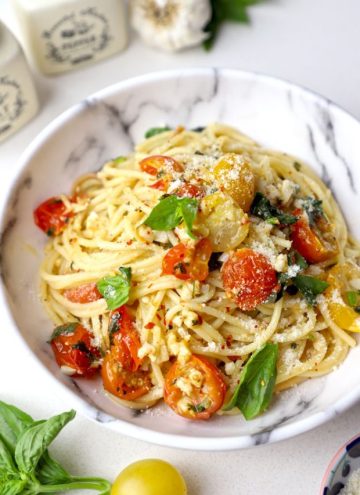 side close up shot of cherry tomato pasta in a white ceramic bowl