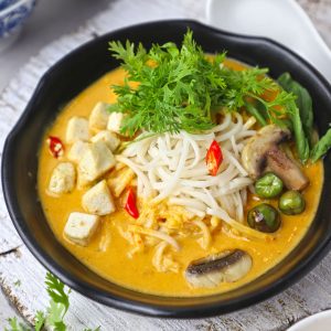 side close up shoot of laksa soup in a black bowl