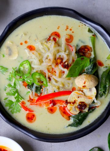 aerial shot of Thai green curry soup served in a black bowl.