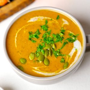 side close up shot of carrot ginger soup in a mug.